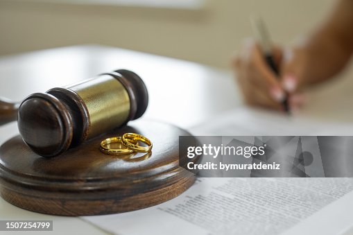 Weeding rings and gavel with a person signing a contract Weeding rings and gavel with a person signing a contract