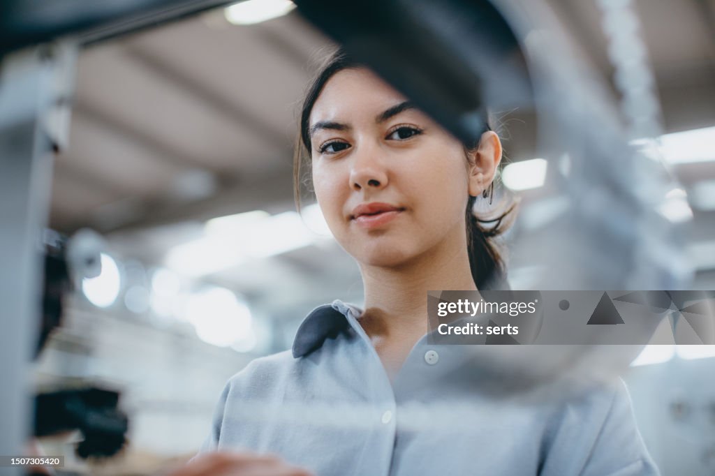 Female industrial worker working with manufacturing equipment in a factory