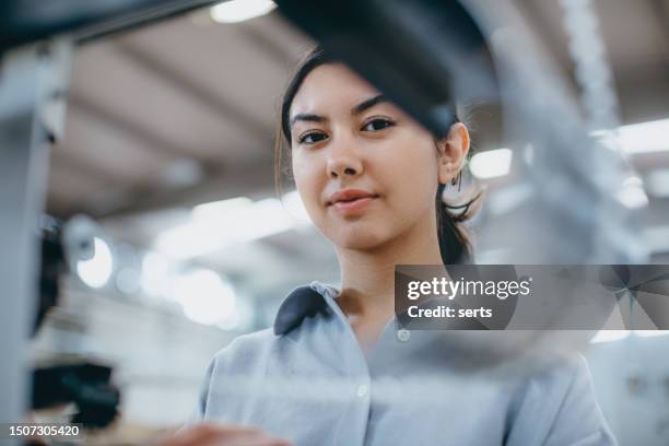 female industrial worker working with manufacturing equipment in a factory - maquinaria de fabrico imagens e fotografias de stock