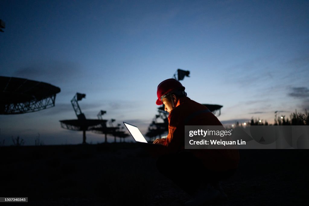 Engineer in hard hat working with laptop.