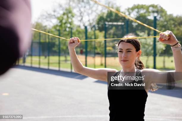 a women sports training at her local park with a fitness instructor - human muscle stock pictures, royalty-free photos & images