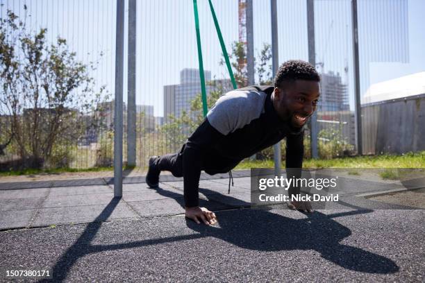 a man doing press ups using a resistance band at an outside gym in the city - pursuit sports competition format stock pictures, royalty-free photos & images