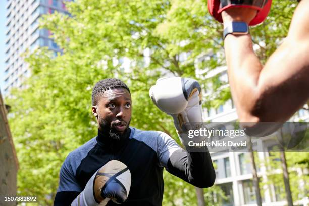 a man boxing training with his fitness instructor outside in an urban city park - human muscle stock pictures, royalty-free photos & images