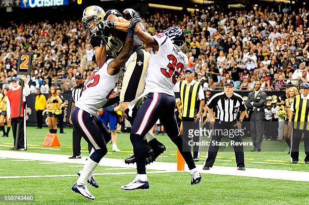 Kareem Jackson and Danieal Manning of the Houston Texans defend as Jimmy Graham of the New Orleans Saints catches a touchdown pass during a preseason...