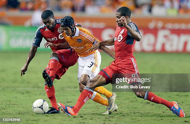Calen Carr of the Houston Dynamo attempts to dribble the ball through Ashtone Morgan of the Toronto FC and Ryan Johnson of the Toronto FC in the...