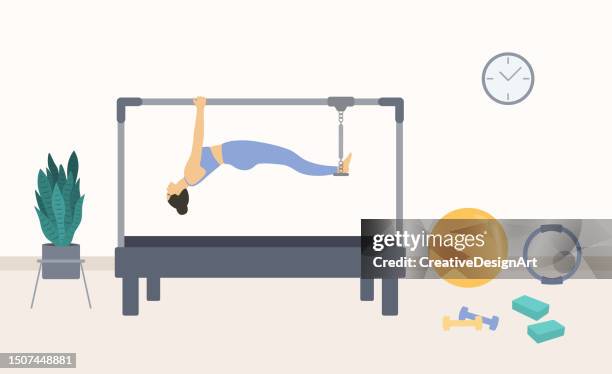 illustrazioni stock, clip art, cartoni animati e icone di tendenza di giovane donna che fa esercizio su cadillac reformer. interni dello studio di pilates con tavolo a trapezio, palla fitness, anello pilates e pianta in vaso. sport e allenamento fitness - cadillac pilates