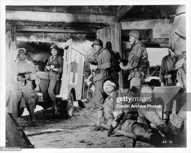 Clint Walker lays on a stretcher with a bandage on his head as Jim Brown, Tom Busby, Donald Sutherland and Ben Carruthers raid the enemy headquarters...