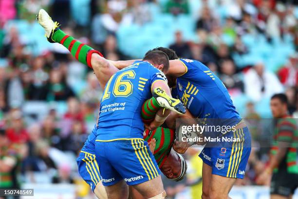 Micahel Crocker of the Rabbitohs is tackled by Justin Poore and Nathan Hindmarsh of the Eels during the round 25 NRL match between the South Sydney...