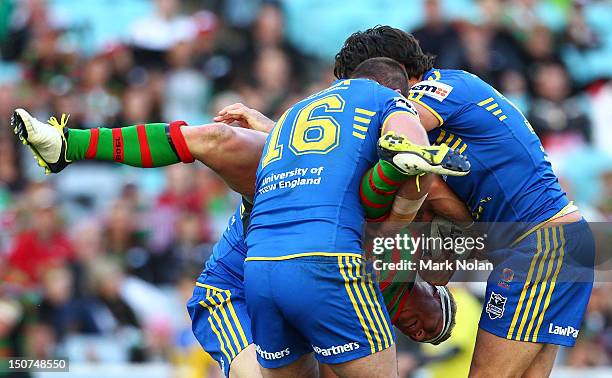 Micahel Crocker of the Rabbitohs is tackled by Justin Poore and Nathan Hindmarsh of the Eels during the round 25 NRL match between the South Sydney...