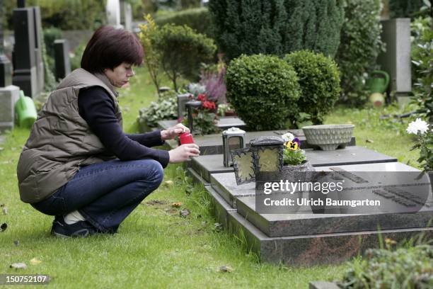 Woman lights a memorial candle on a cemetery.