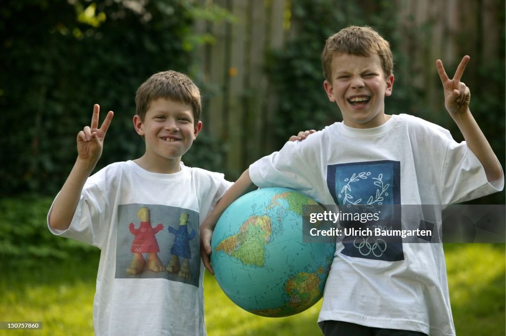 Two boys with shirts of the olympic games 2004 in Athens ( left: mascots of the olympic games, Athena and Phevos, right: the olympic symbol and a globe.