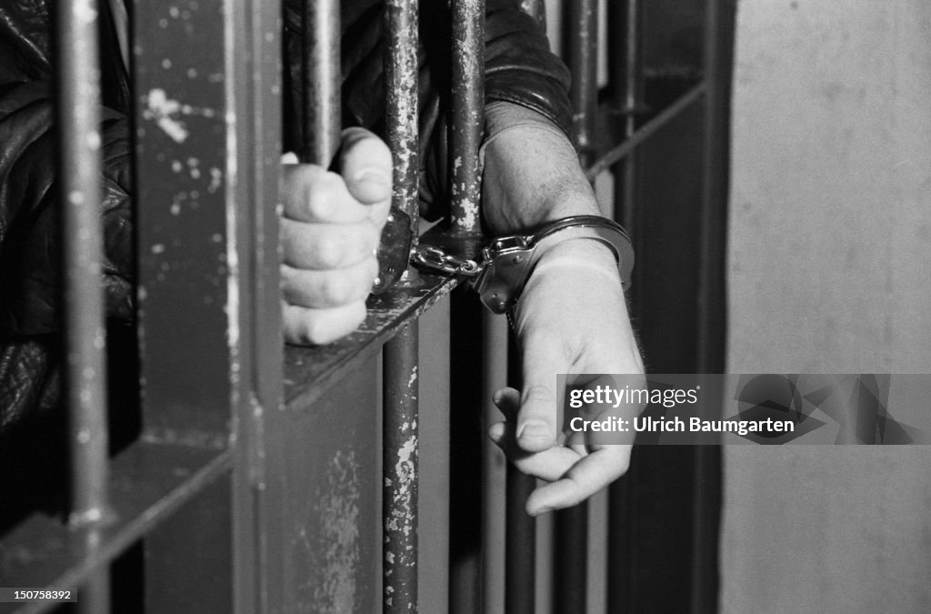 Symbolic photo to the topics: prison, justice, et, Our picture shows hands in handcuffs behind bars.