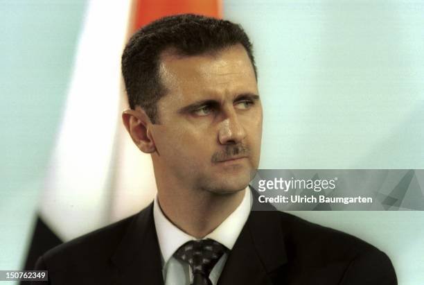 Bashar AL-ASSAD, state president of Syria, in front of the Syrian flag.