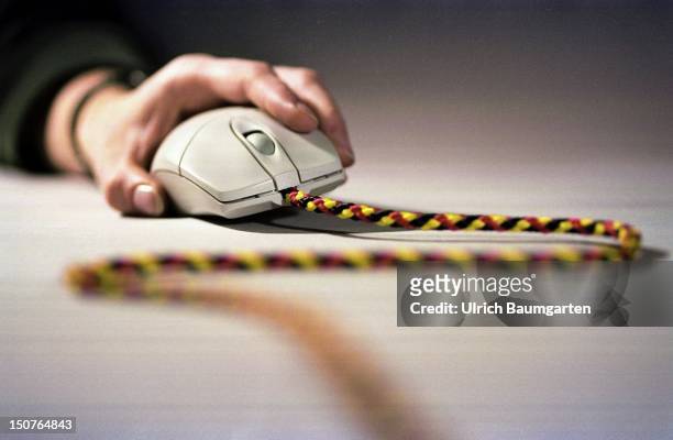 One hand holds a computer mouse with a black, red and gold cord as cable.