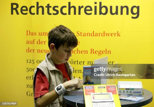 Boy at a stable of the book fair in Frankfurt, In the back the writing - Rechtschreibung - on a outsized Duden of the German orthography.