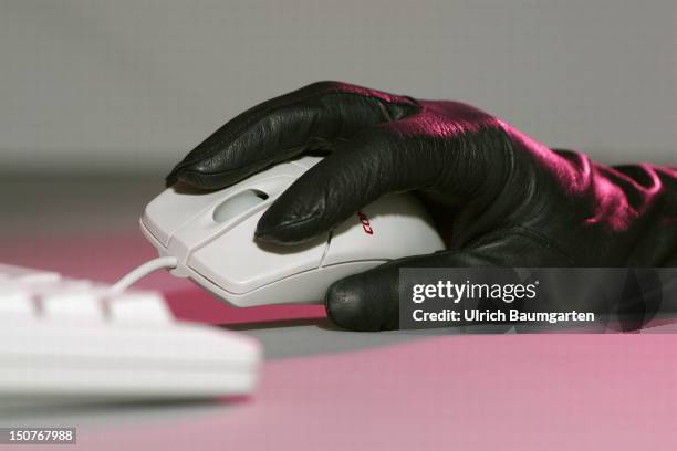 Symbolic picture: computer crime, Hand with a black clove is holding a computer mouse, In the foreground a computer keyboard.