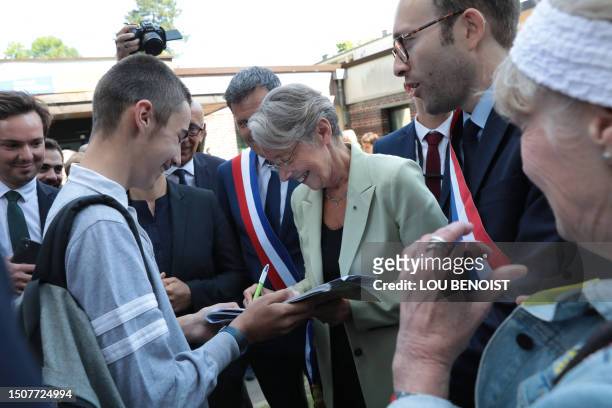 French Prime Minister Elisabeth Borne writes a note of apology to a pupil who came to listen to her during her visit to the town of Lisieux in...
