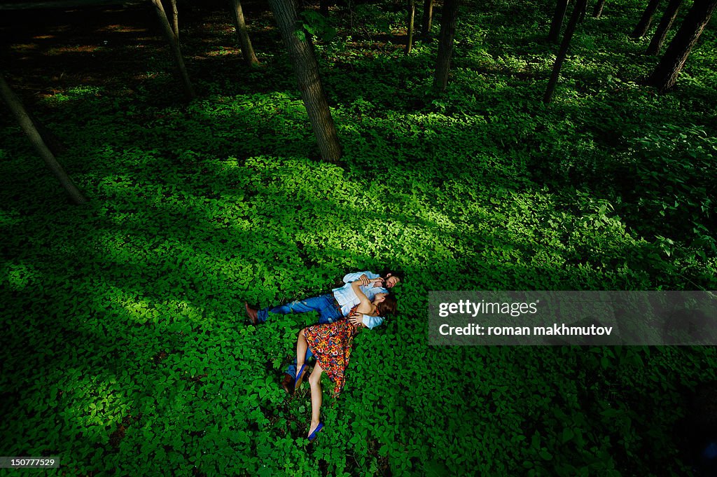 Young couple laying in green forest