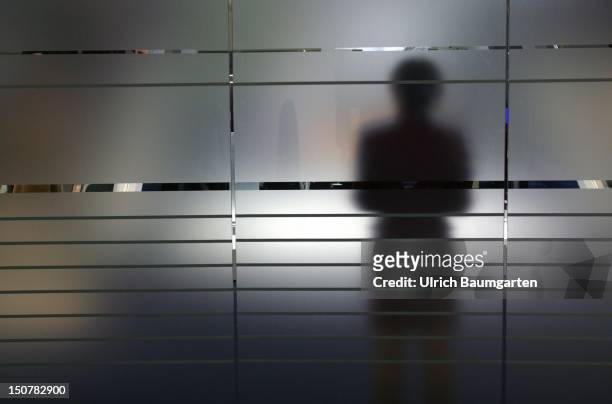 Shadow of a woman on a frosted glass pane, Symbolic photo to the topics: anonymity, fear, uncertainty, unsteadiness, personal secrets etc.