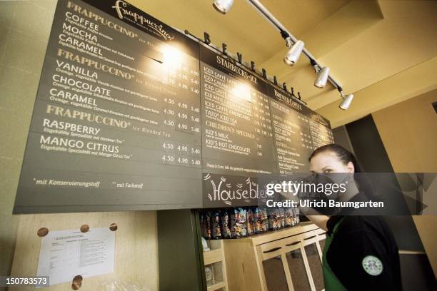 Employee at a price board in a Starbucks coffee house in Berlin.