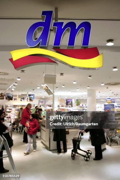 Bonn, Logo of a dm Drogerie-Markt and interior view of a dm store with shopping customers.