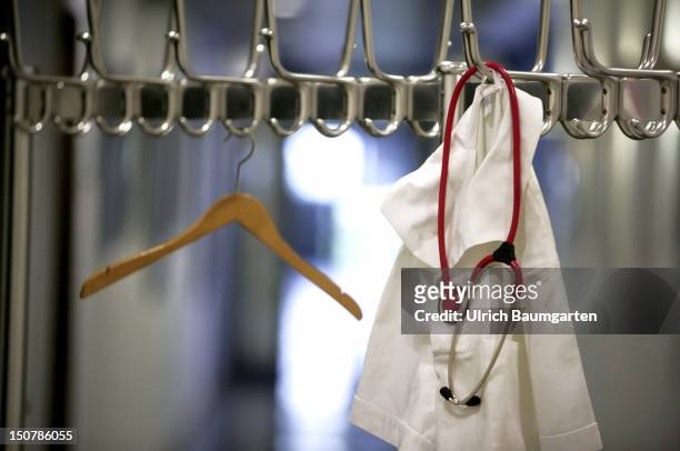 Medical scrubs and a stethoscope hanging on a coat stand.