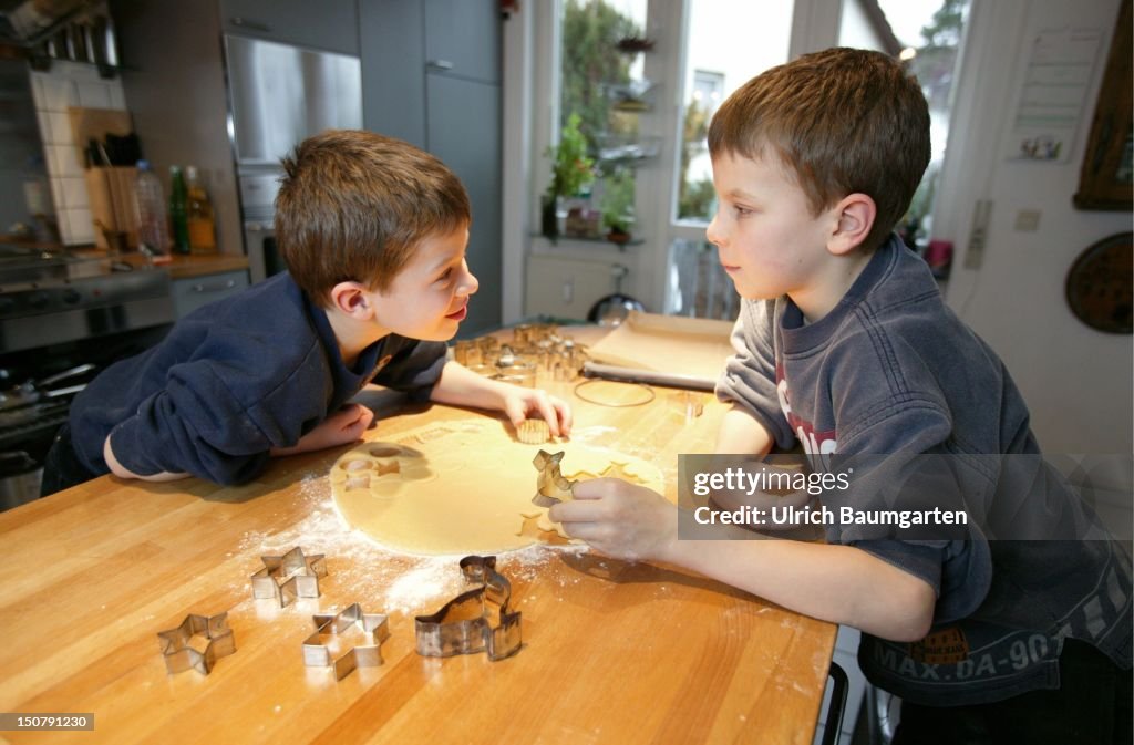 Two boys ( 9 and 7 years old ) at the backing of Christmas cookies / biscuits.