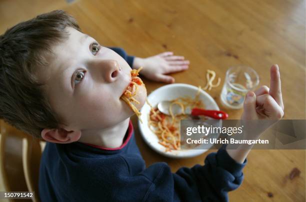 Boy eat spaghetti with gesture - fuck you -, Symbol picture about bad behave, bad table manners of children.