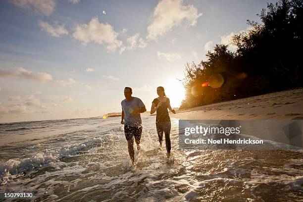 a couple runs together at the beach - pacific stock-fotos und bilder