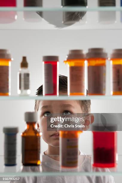 young boy looking into a medicine cabinet - badezimmerschrank stock-fotos und bilder