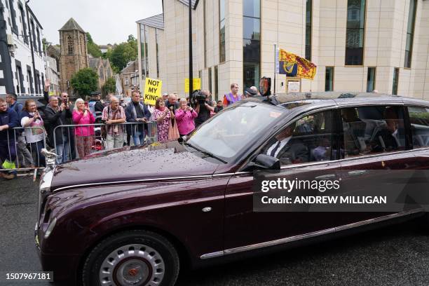 Britain's King Charles III and Britain's Queen Camilla drive past protesters after a visit to The great Tapestry of Scotland visitor centre in...