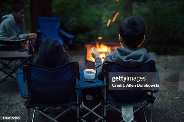 family sitting at camp fire at night - simple living stock pictures, royalty-free photos & images