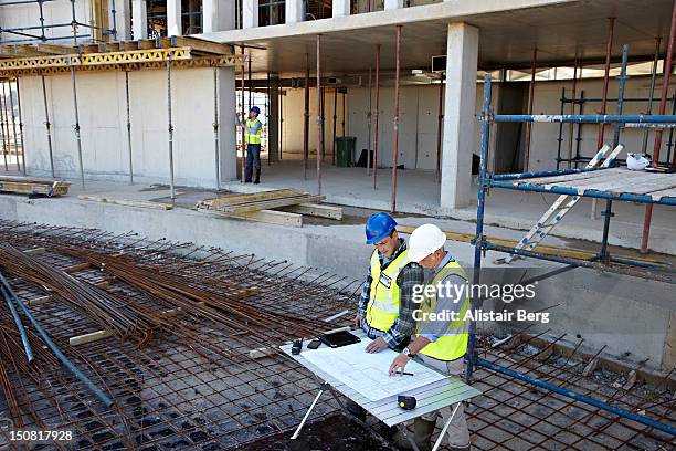 builder and engineer looking at construction plans - engenheiro civil imagens e fotografias de stock