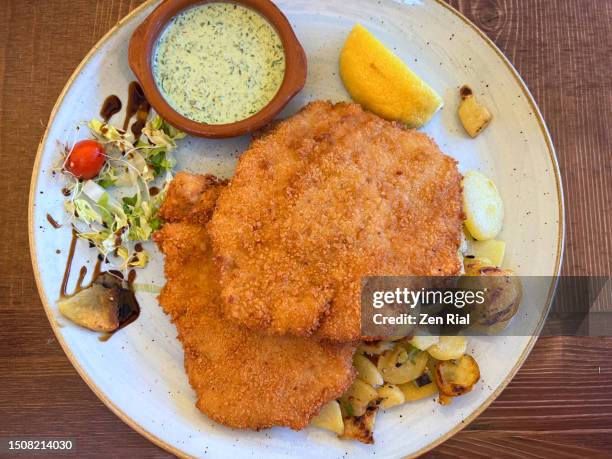 schnitzel served with slice of lemon, potatoes and creamy sauce - empanado fotografías e imágenes de stock