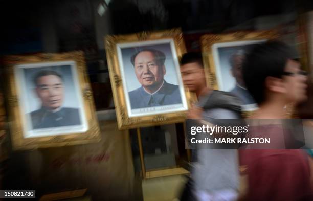 Pedestrians walk past portraits of past leaders including Zhou Enlai and Mao Zedong as the city prepares for the upcoming 18th National Congress of...