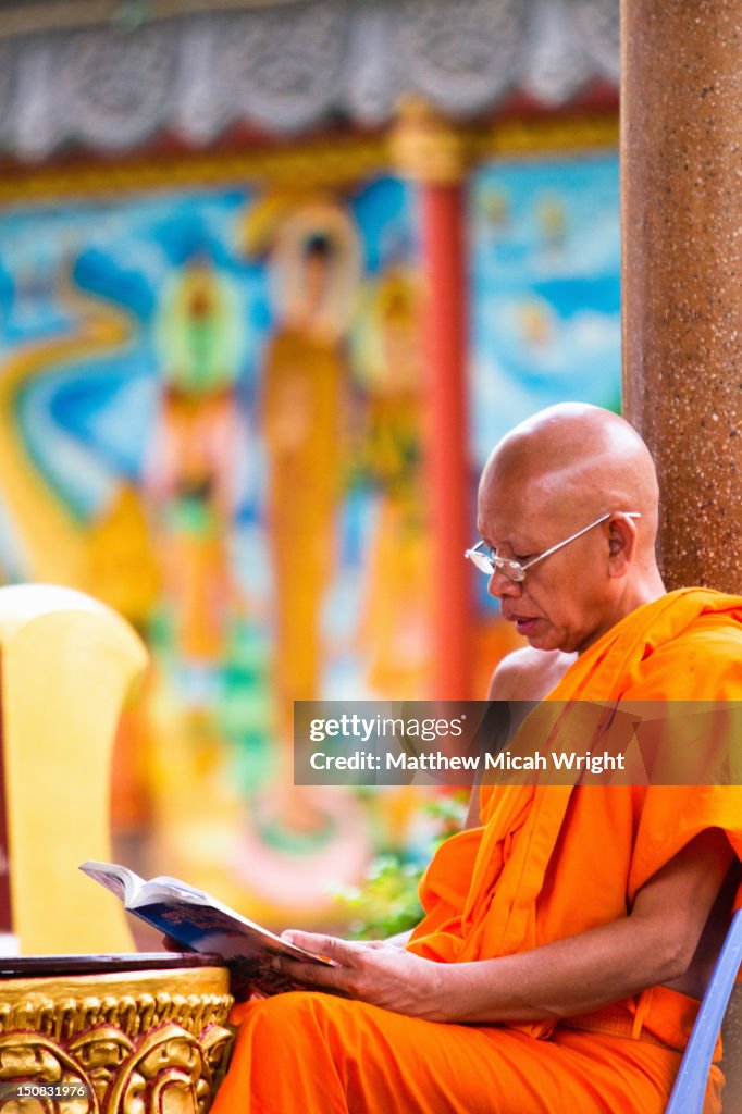 A Buddhist monks sits and reads.