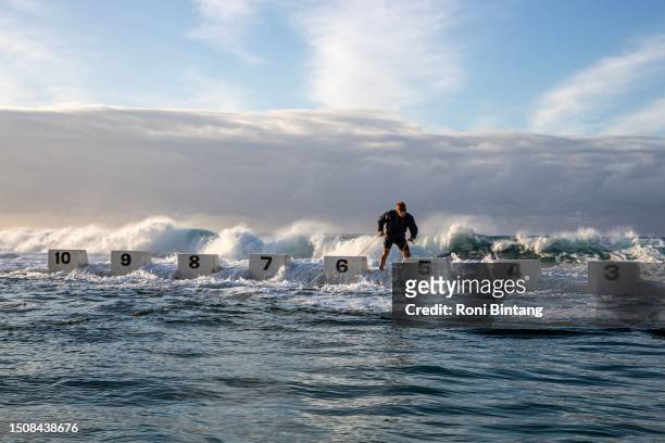 Man prepares lane ropes before a winter swimming competition held by Merewether Mackerels swimming club at Merewether Ocean Baths on July 02, 2023 in...