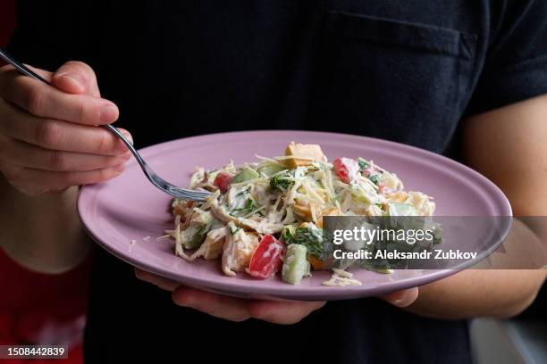 greek salad with cheese, tomatoes and cucumber. the concept of healthy eating. delicious and healthy vegetarian dish, snack. high-calorie salad on a plate, on a wooden table in a cafe or restaurant. a man eats a salad at the dining table, at home. - greek salad stock pictures, royalty-free photos & images