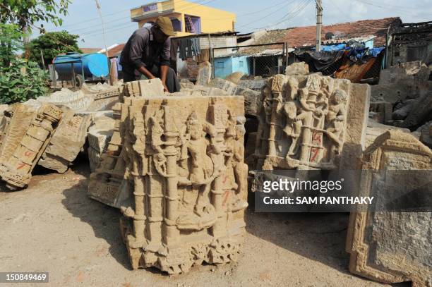 Gopalbhai, an Indian skilled worker from the Archaeological Survey of India examines ancient stone carvings from the facade of an ancient temple at...