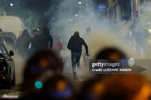 Demonstrators run as French police officers use tear gas in Paris on July 2 five days after a 17-year-old man was killed by police in Nanterre, a...