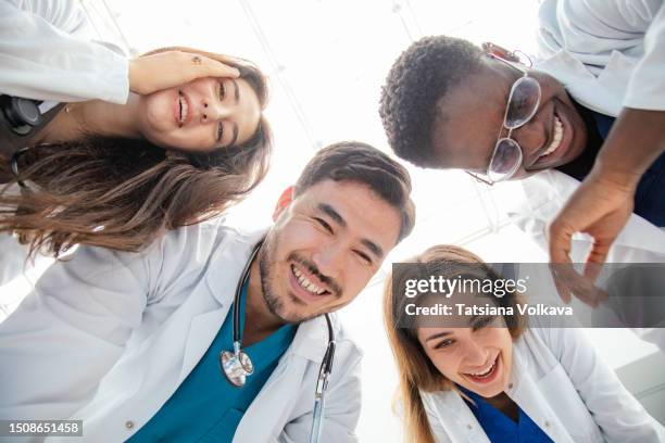 photo of a group of people of 4 medical workers who are bending over looking down and laughing merrily - tears of joy stock pictures, royalty-free photos & images
