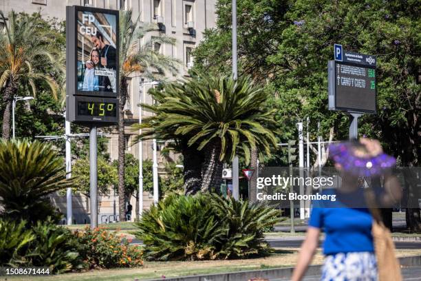 Pedestrian carry a fan passes a temperature indicator reading 45C during high temperatures in Prado de San Sebastian gardens in Seville, Spain, on...