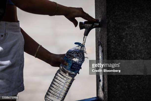 Pedestrian fills a water bottle from a fountain during high temperatures in Seville, Spain, on Wednesday, July 5, 2023. Global temperatures hit a...