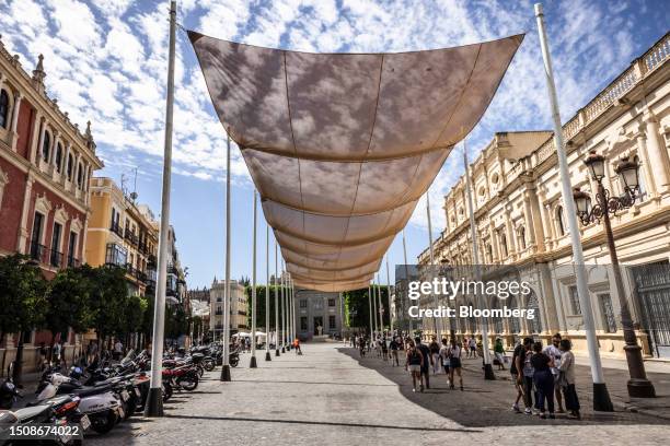 Pedestrians in the shade of a sun awning during high temperatures near City Hall in central Seville, Spain, on Thursday, July 6, 2023. Global...