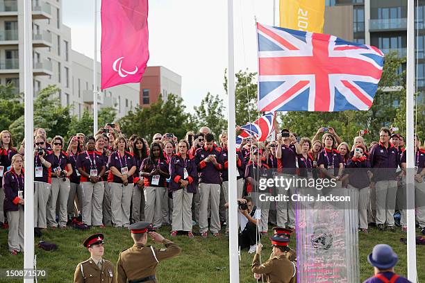 Volunteers look on as the Union Jack is raised during a welcome ceremony at the Paralympic Village on August 28, 2012 in London, England.