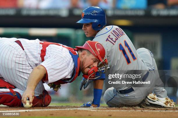 Erik Kratz of the Philadelphia Phillies reaches back for the ball as Ruben Tejada of the New York Mets slides safe into home in the first inning at...