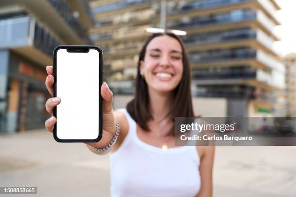 cheerful woman showing cellphone to the camera. - exhibir fotografías e imágenes de stock