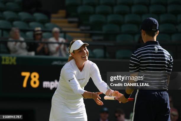 Ball boy gives back the racket to Croatia's Donna Vekic after she threw it on the ground after missing to score a point against US player Sloane...