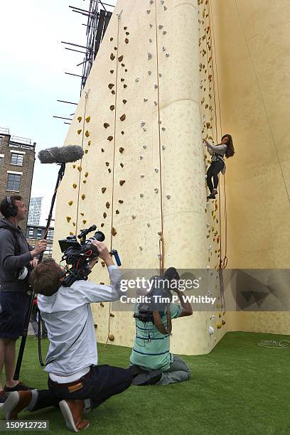 Katie Price climbs a wall as she attends the launch of Walkers Deep Ridged crisp at The Old Truman Brewery on August 29, 2012 in London, England.