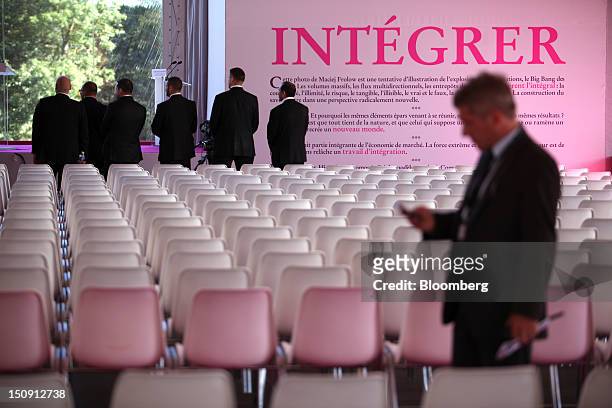 Businessmen stand amongst empty seats in the main plenary hall before sessions begin at the Mouvement des Enterprises de France conference at Campus...